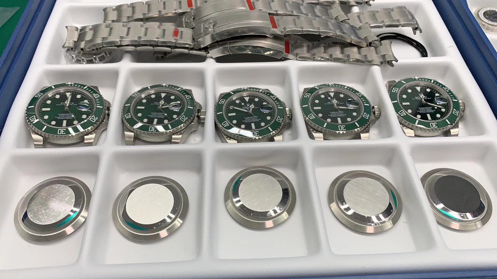 Replica Rolex parts including cases, bezels, and bracelets showing manufacturing quality