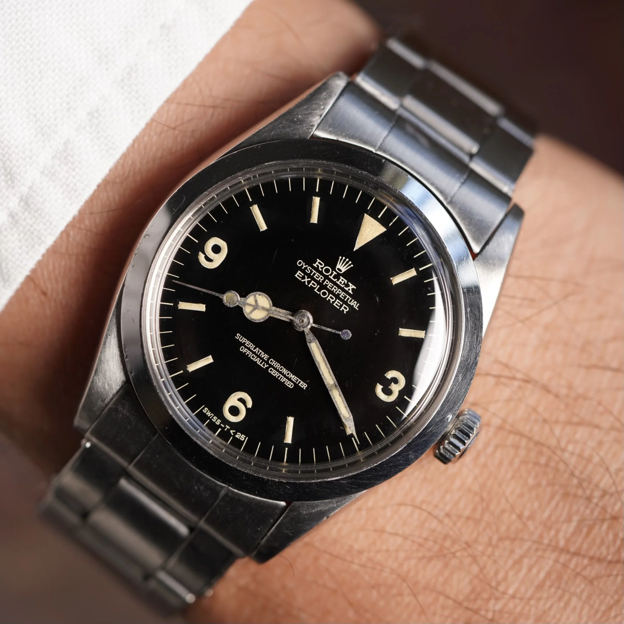 Macro of a 1960s gilt Rolex Explorer ref. 1016 dial — gold-toned text printed on glossy black lacquer, with spidering and patina that make every original gilt dial one-of-a-kind.